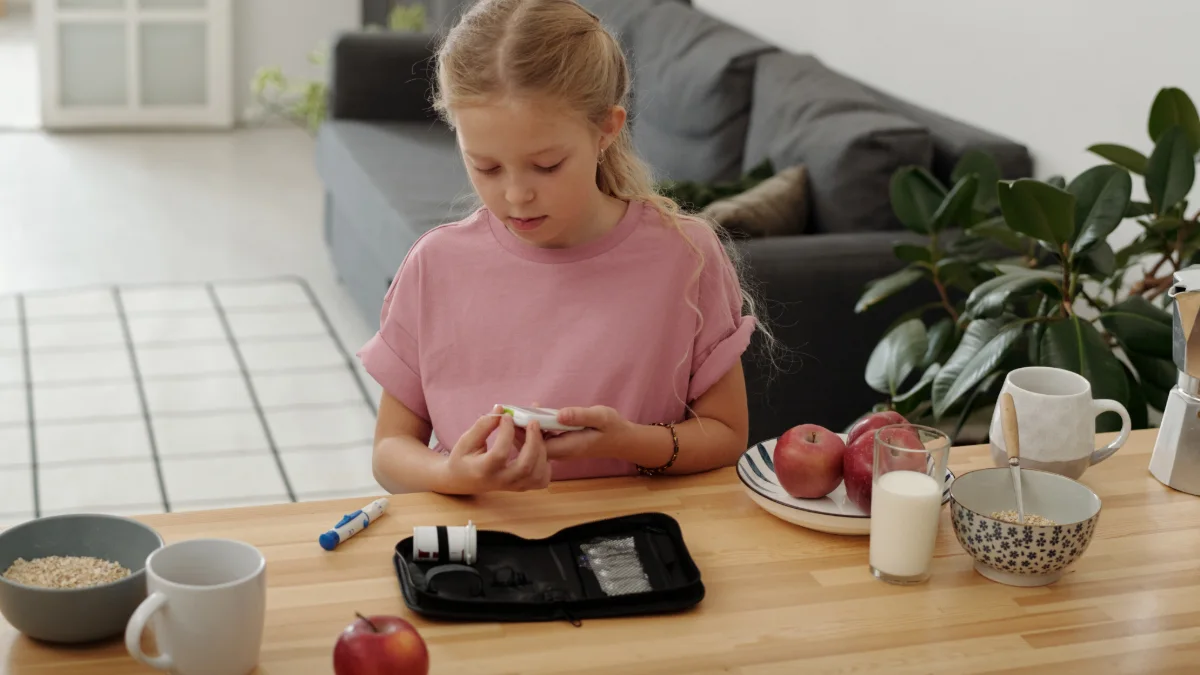 Menina medindo a glicemia com glicosímetro à mesa