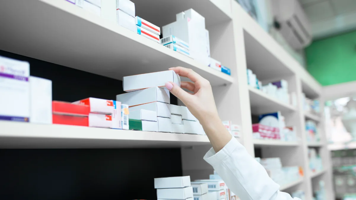 Farmacêutica retirando uma caixa de medicamento da prateleira