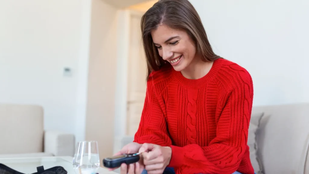 Mulher sorrindo enquanto mede a glicemia em casa