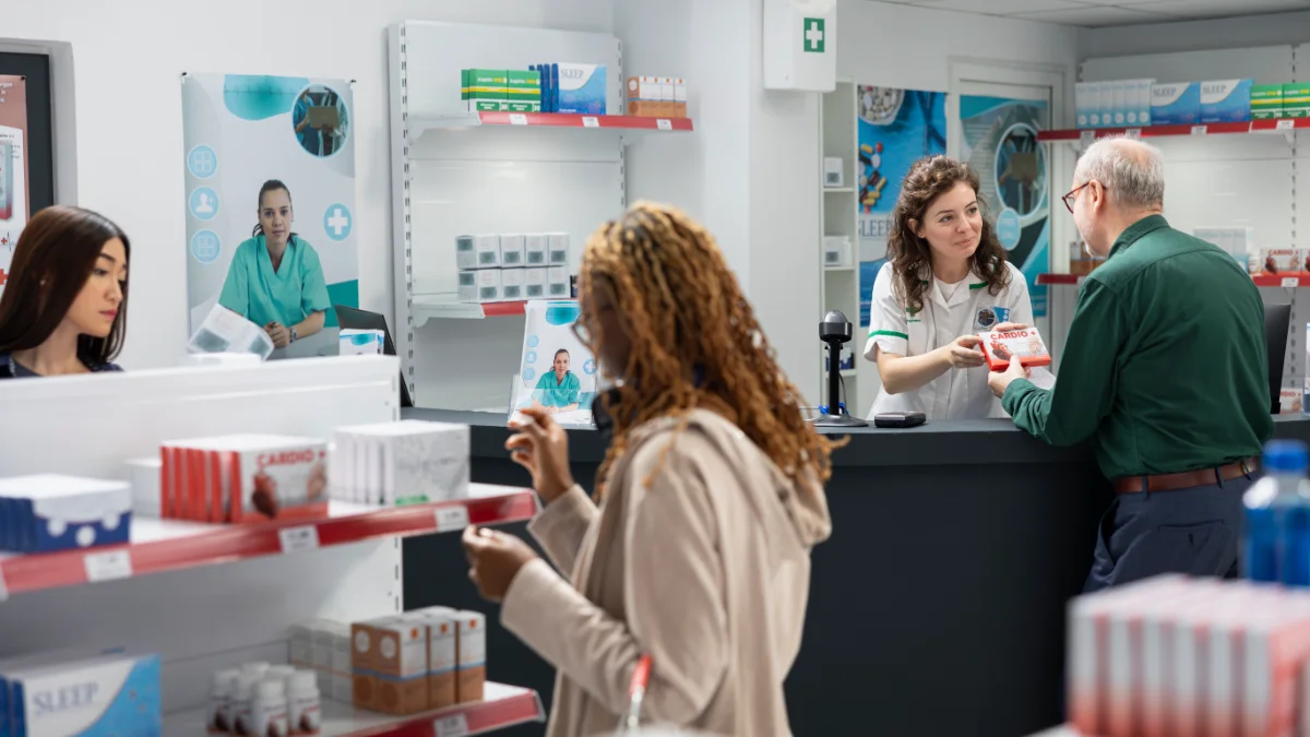 Atendente de farmácia entregando medicamento a um paciente idoso no balcão