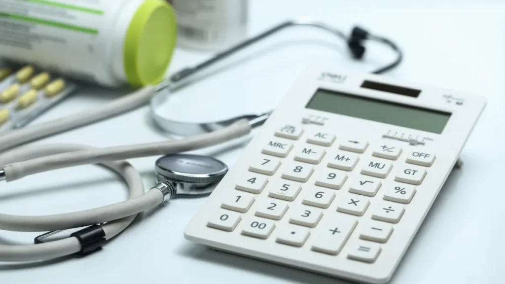 Calculadora, estetoscópio e frascos de medicamento sobre fundo branco