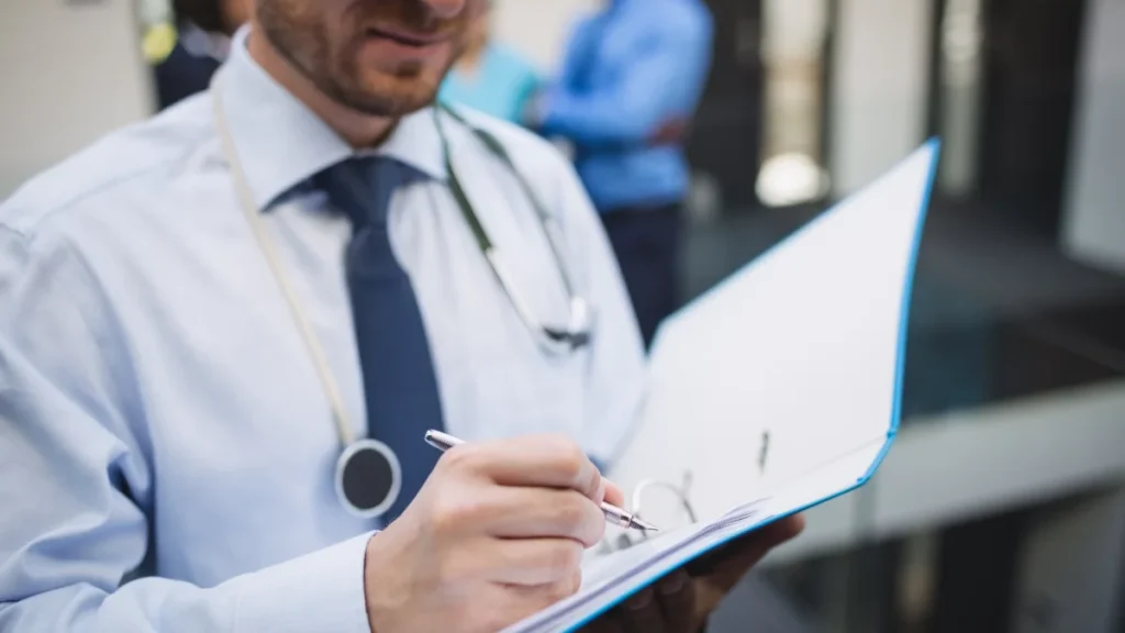 Médico escrevendo um relatório numa prancheta