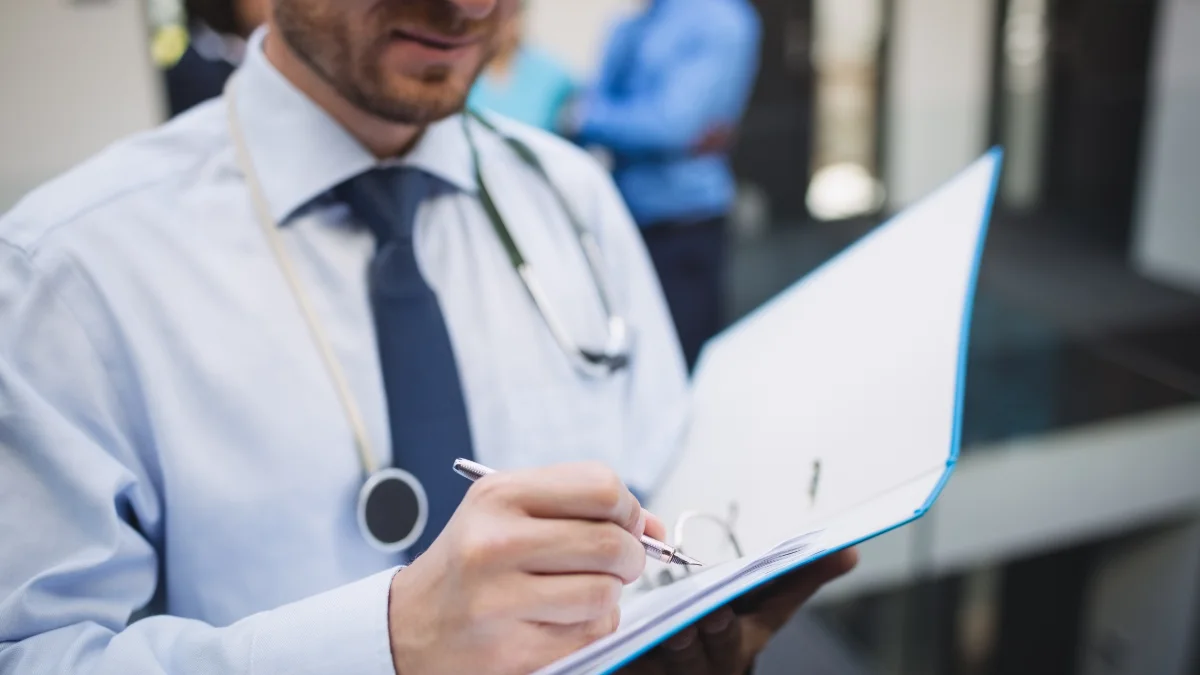 Médico escrevendo um relatório numa prancheta