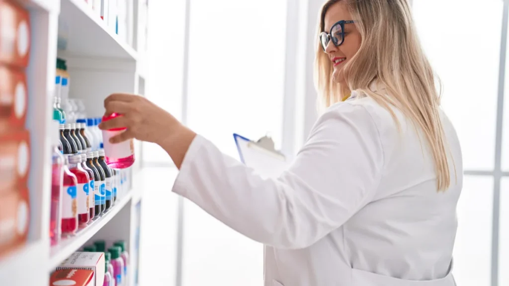 Farmacêutica lendo um documento e segurando um frasco de medicamento